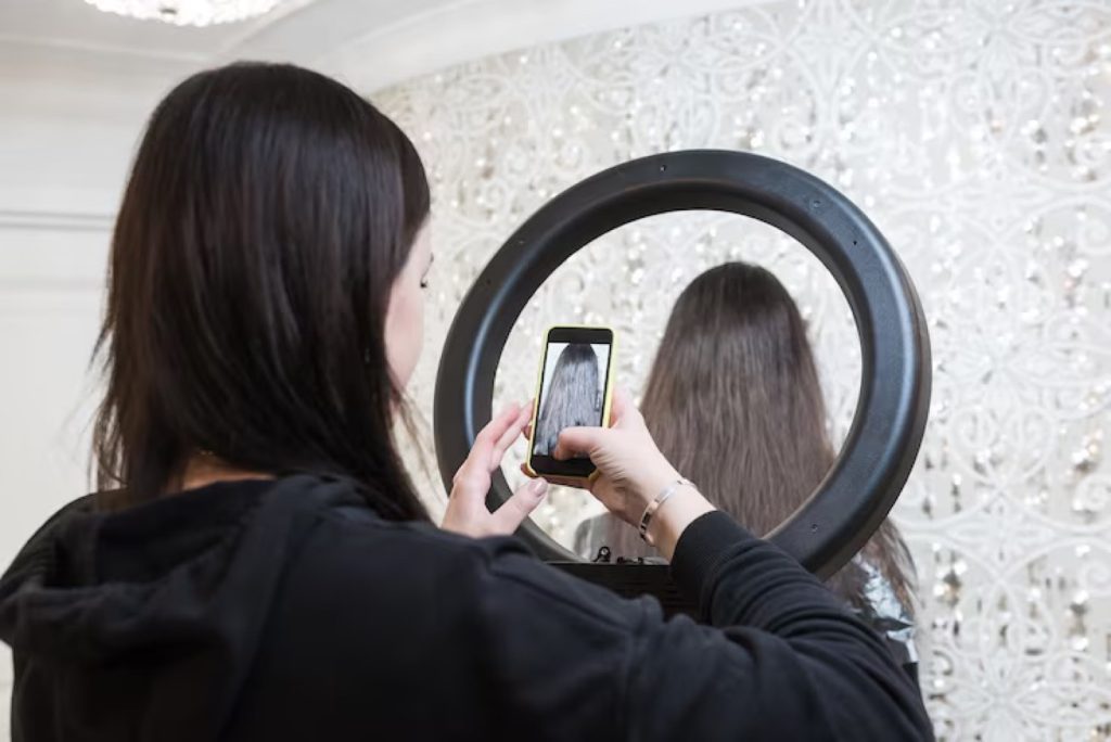 Stylist filming a hair transformation on her phone with a ring light in a private San Antonio salon suite