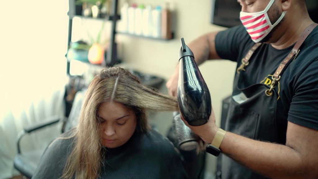 Beauty professional blow-drying a client's hair in a private San Antonio salon suite after receiving a salon consultation fee.