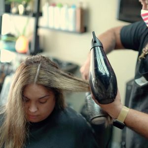 Beauty professional blow-drying a client's hair in a private San Antonio salon suite